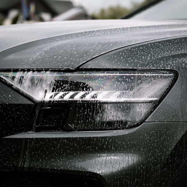 A vertical shot of soap on a black shiny modern car at daytime